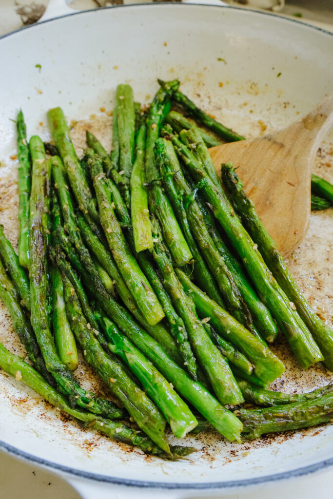 Close-up of crispy pan fried asparagus with charred tips in a skillet.