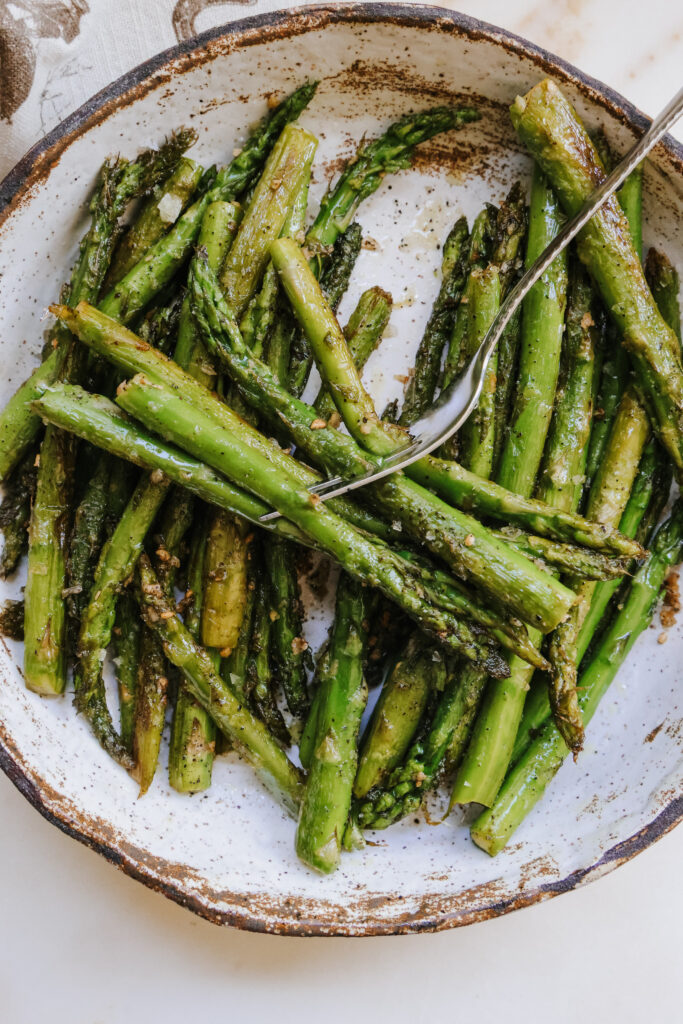 Close-up of pan fried asparagus plated with a fork resting on top