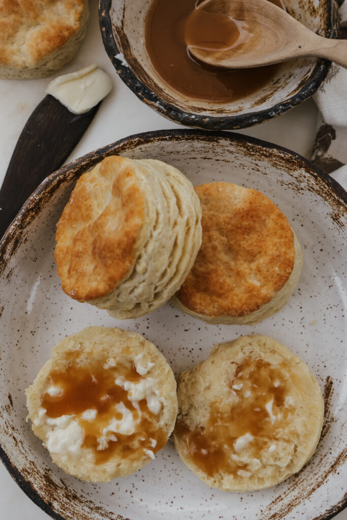 Homemade buttermilk biscuits in a bowl served with honey and butter