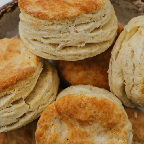 Close up of golden biscuits with flaky layers in a rustic bowl