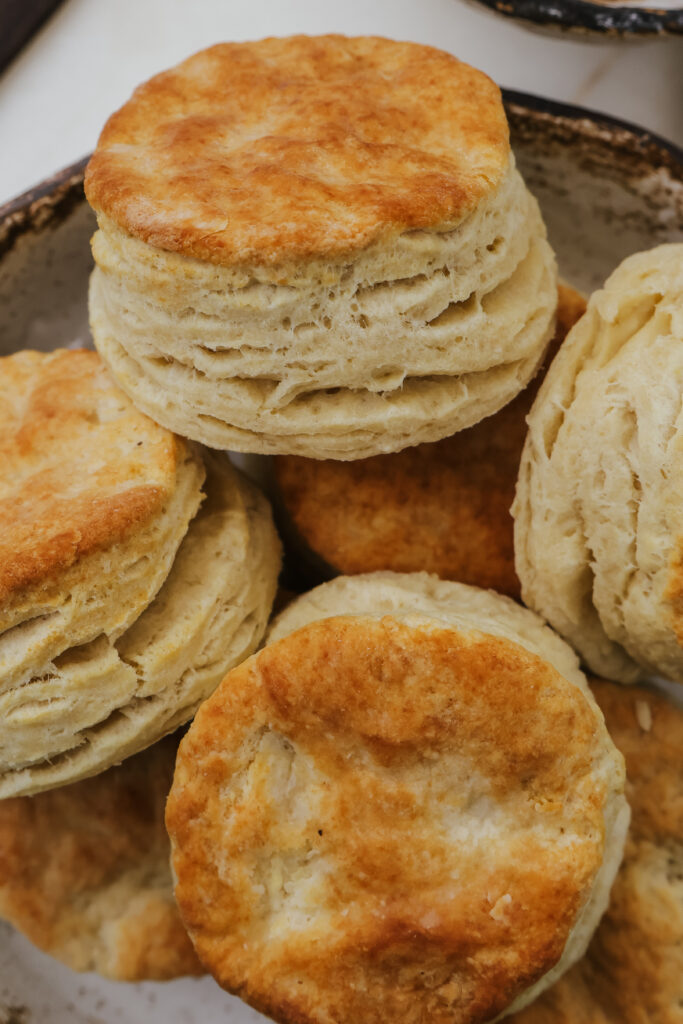 Close up of golden biscuits with flaky layers in a rustic bowl