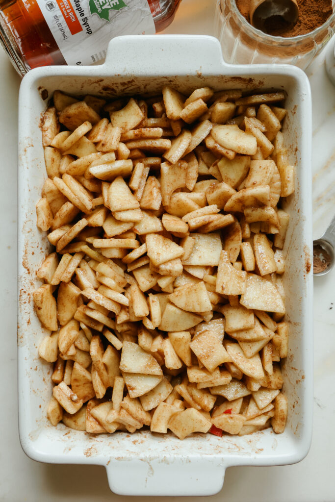 Softened apples in maple syrup sauce in a casserole dish, ready for the oat topping