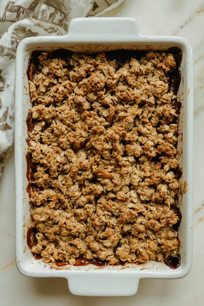 Baked healthy apple crisp with maple syrup in a casserole dish, golden oat topping
