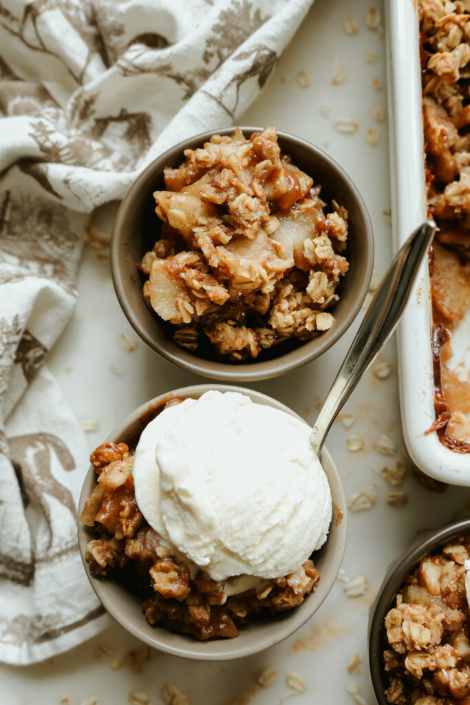 Healthy apple crisp with maple syrup topped with a scoop of vanilla ice cream