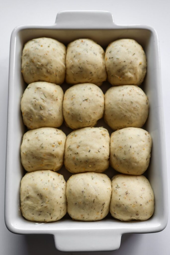 rosemary rolls that have risen in a casserole dish and they are now ready to bake.