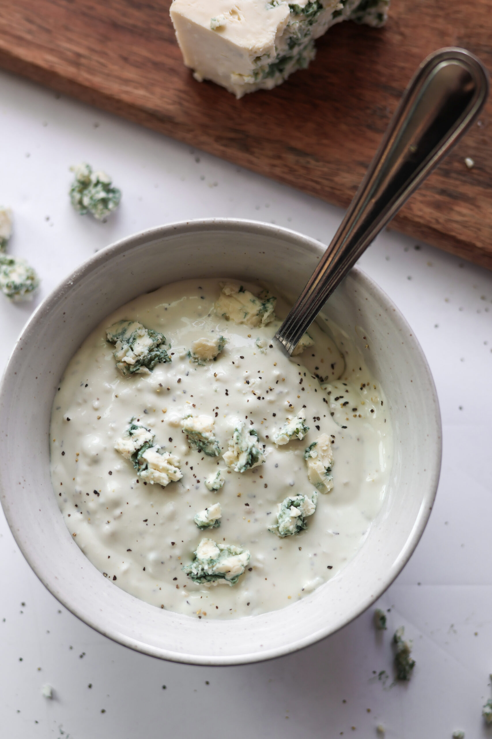Creamy homemade blue cheese dressing in a small white bowl with visible blue cheese crumbles.