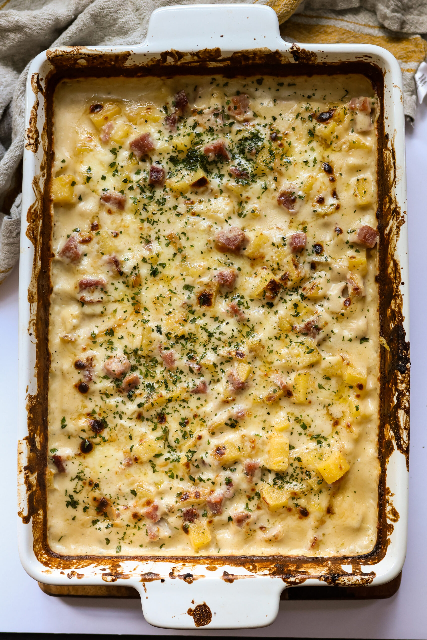 Cheesy ham and potato casserole in a white casserole dish