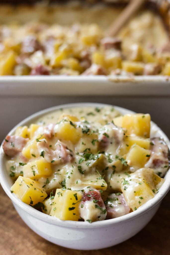 White bowl filled with diced ham, potatoes, and creamy sauce