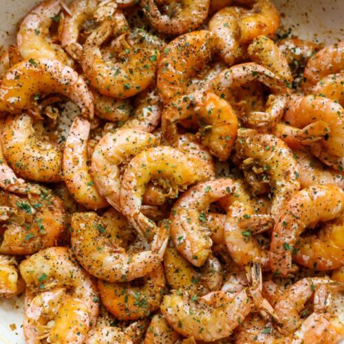Overhead view of a skillet filled with Old Bay peel and eat shrimp, cooked in butter and garlic, garnished with chopped parsley.