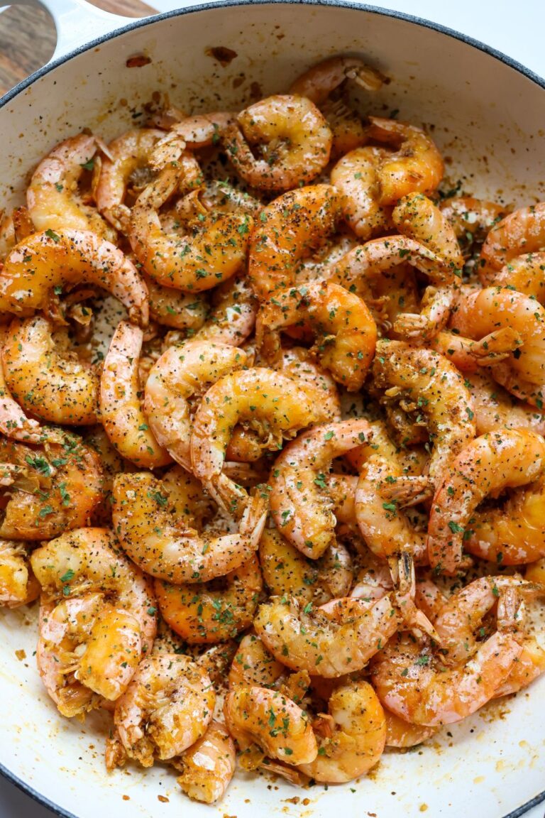 Overhead view of a skillet filled with Old Bay peel and eat shrimp, cooked in butter and garlic, garnished with chopped parsley.