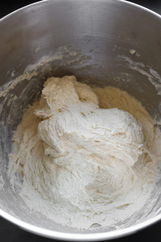 Easy pizza dough recipe with all-purpose flour in a stainless steel mixing bowl, showing high hydration dough for chewy homemade pizza crust.