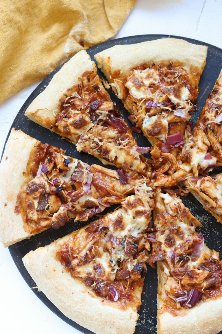 Golden brown BBQ chicken bacon pizza fresh out of the oven with melted mozzarella cheese, crispy bacon, caramelized red onions, and a sprinkle of parmesan cheese