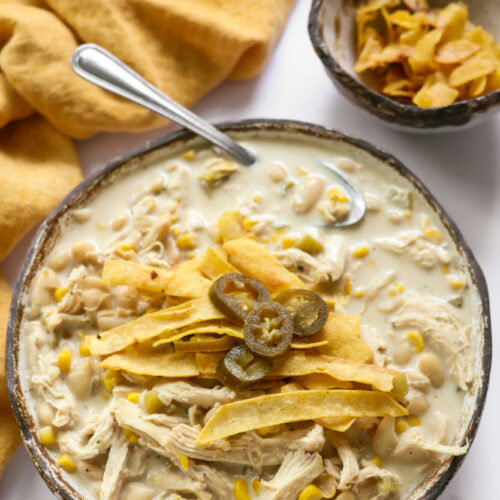 creamy white chicken chili with cream cheese served in a bowl topped with tortilla strips