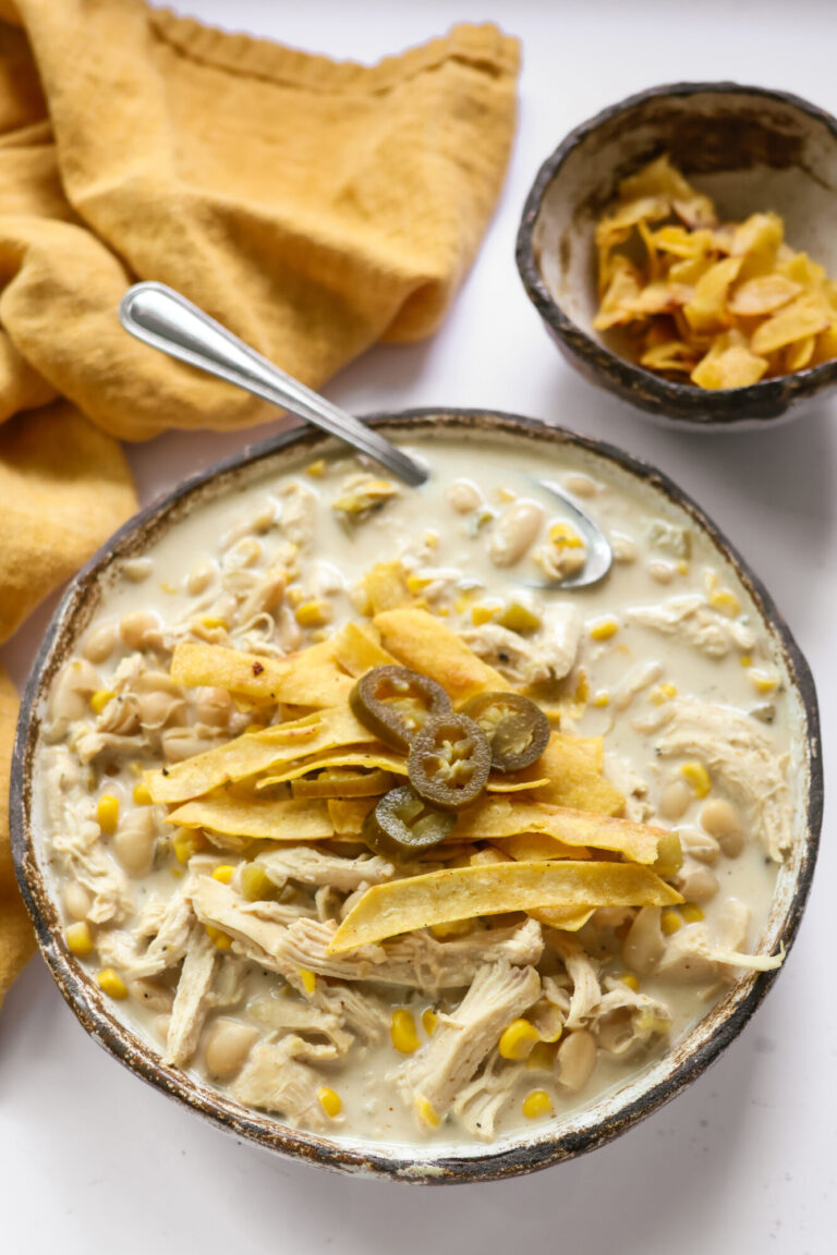 creamy white chicken chili with cream cheese served in a bowl topped with tortilla strips