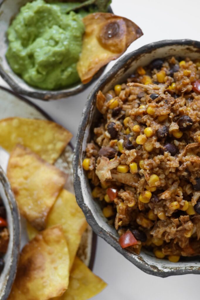 Crockpot Mexican chicken with black beans, corn, and rice in a handmade pottery bowl