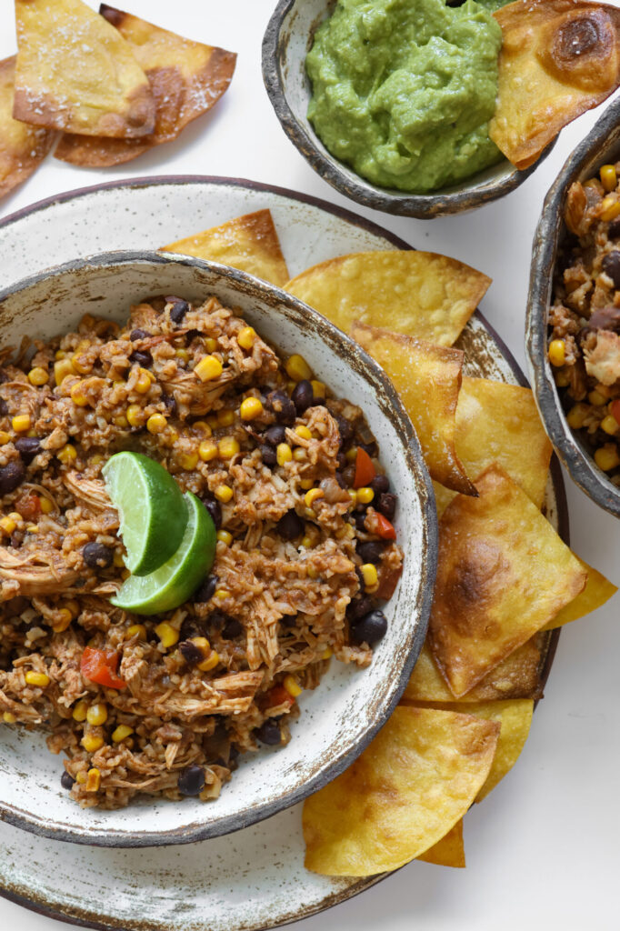 Mexican-inspired slow cooker chicken and rice recipe in pottery bowls with lime garnish.