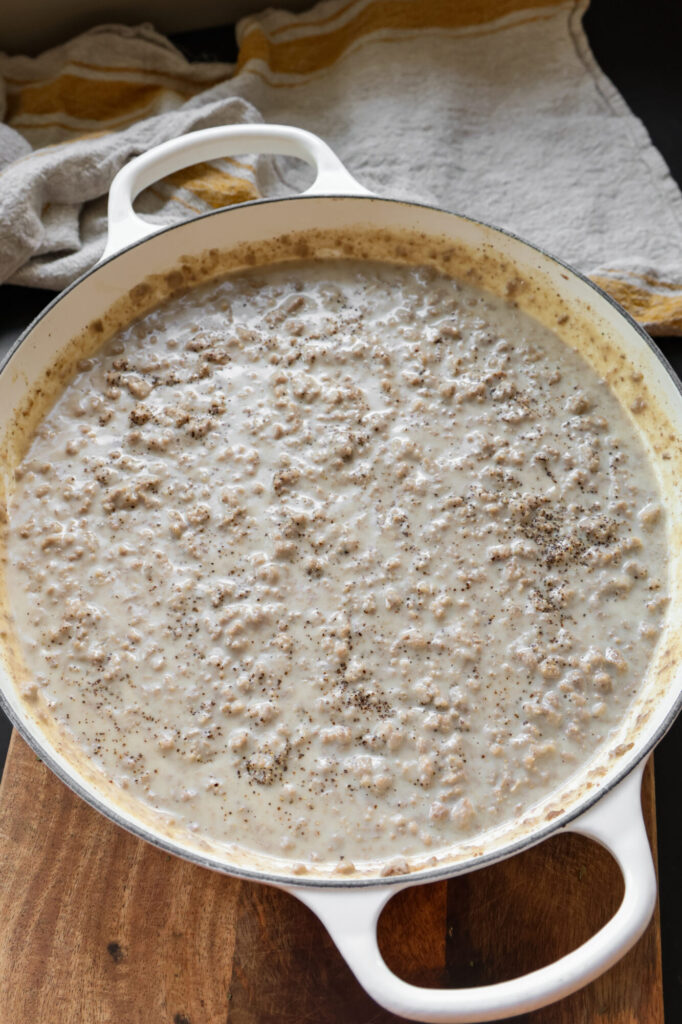 Homemade hamburger gravy simmering in a large skillet with ground beef