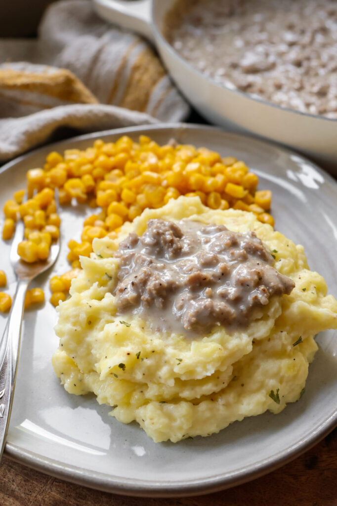 Creamy sour cream mashed potatoes served with homemade hamburger gravy — a cozy comfort food meal for weeknight dinners.