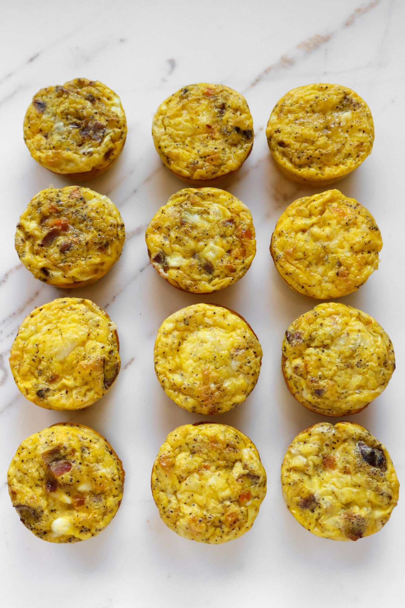 Homemade cottage cheese egg bites with bacon and red bell peppers on a plate – high protein breakfast with creamy texture and cheesy flavor.
