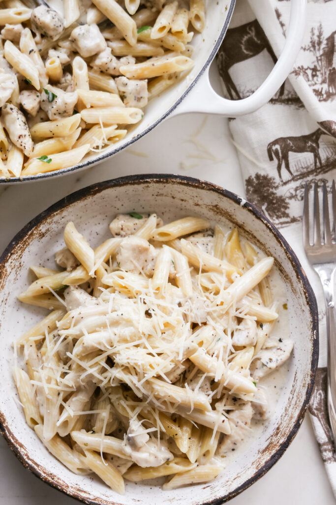 Bowl of chicken Alfredo pasta topped with freshly grated parmesan.