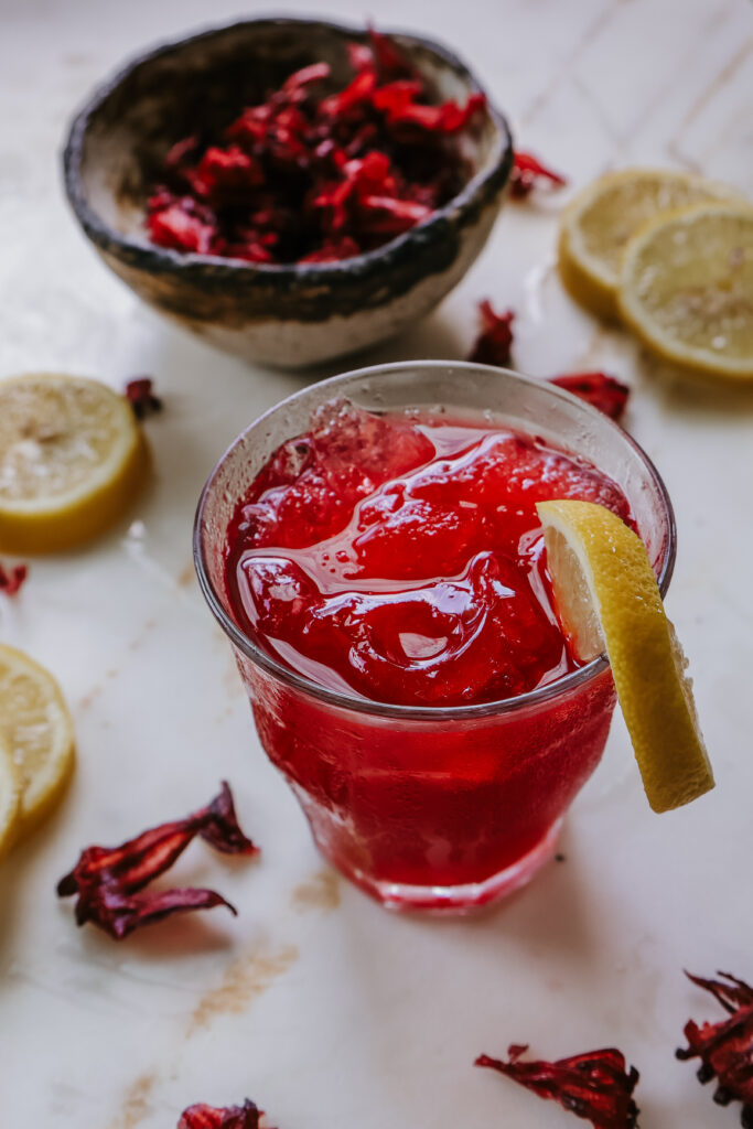 A glass of honey hibiscus lemonade recipe with a deep magenta color.