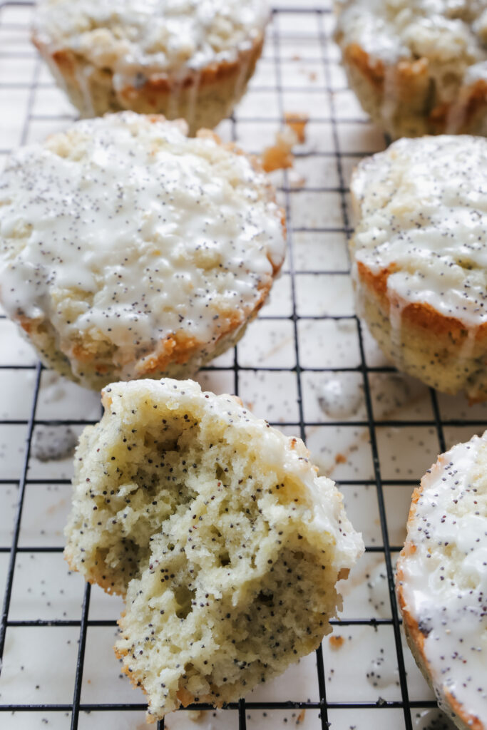 One muffin torn open to show a soft, tender poppy seed crumb on a wire rack