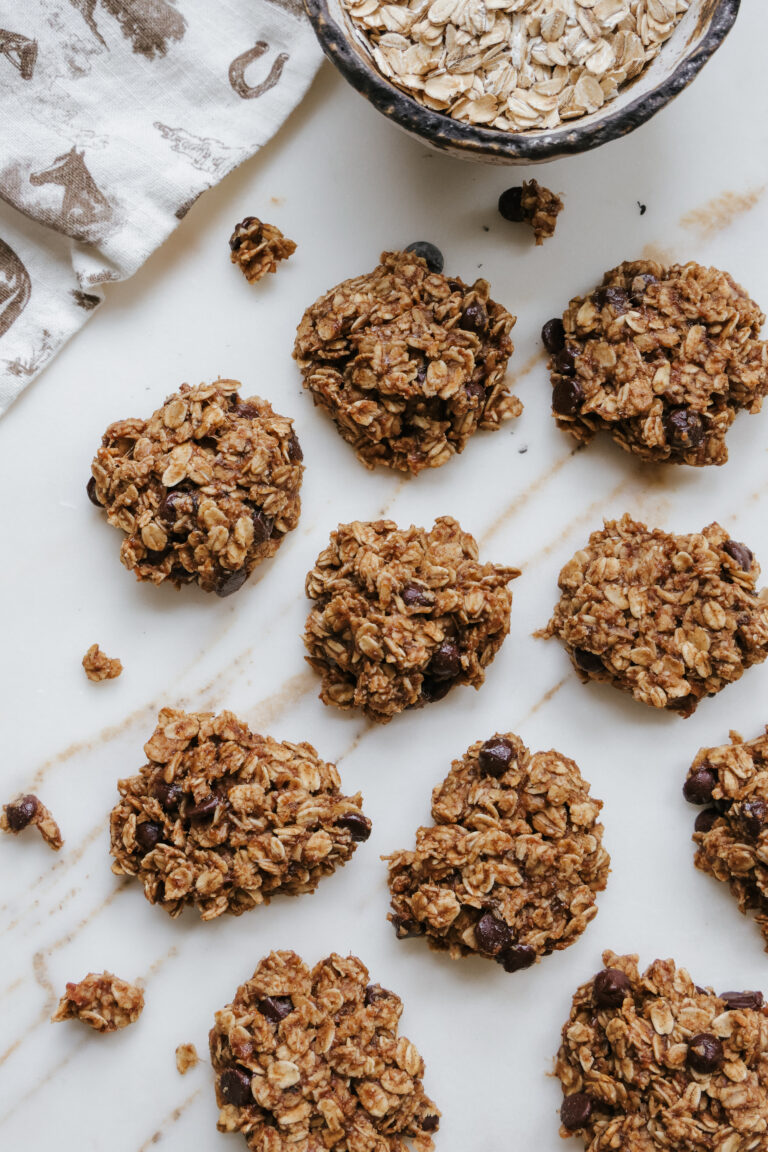 Flat lay of banana oatmeal cookies with melted chocolate chips cooling on a marble countertop