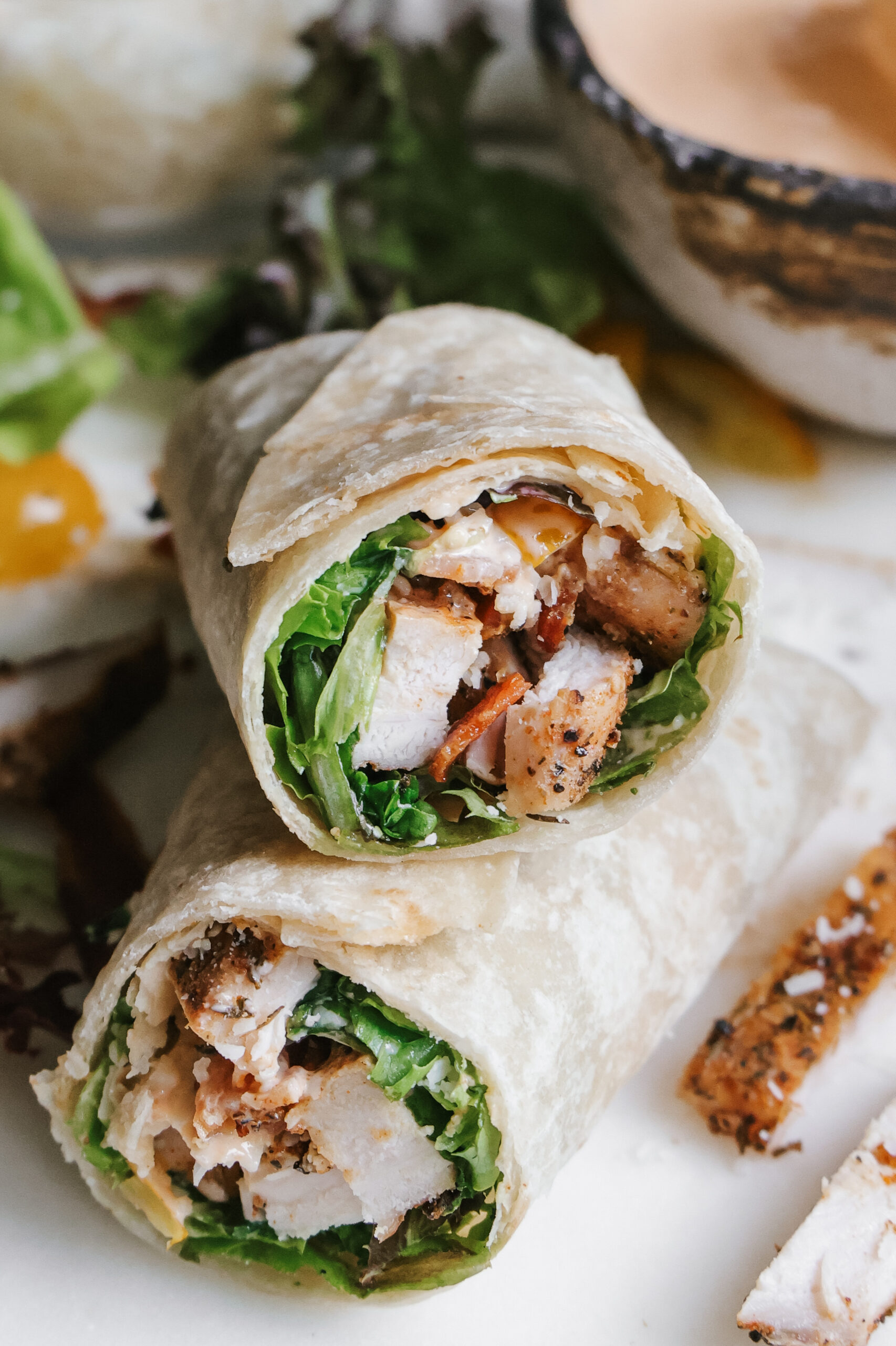 Close-up of a BLT chicken wrap cross section with grilled chicken, bacon, and lettuce
