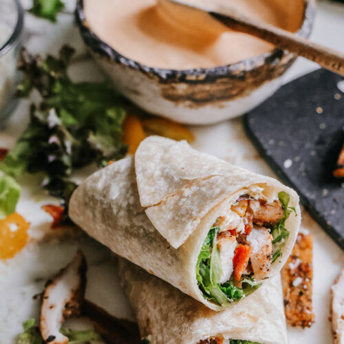 BLT chicken wrap cut in half and stacked, showing the chicken, bacon, and lettuce filling