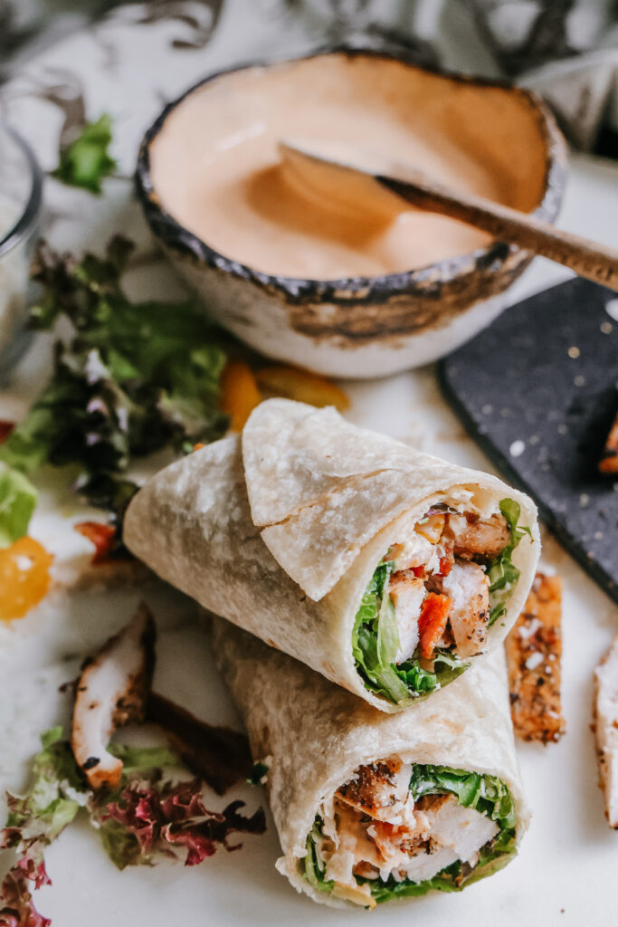 BLT chicken wrap cut in half and stacked, showing the chicken, bacon, and lettuce filling