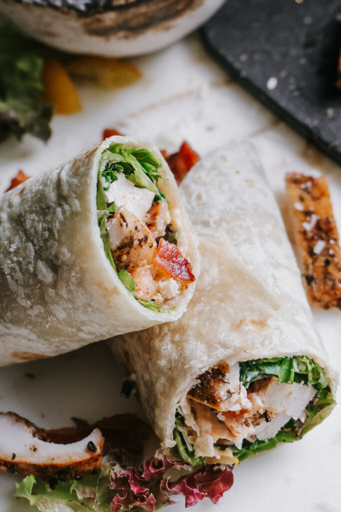Finished BLT chicken wrap sliced in half and ready to serve with parmesan crisps on the side