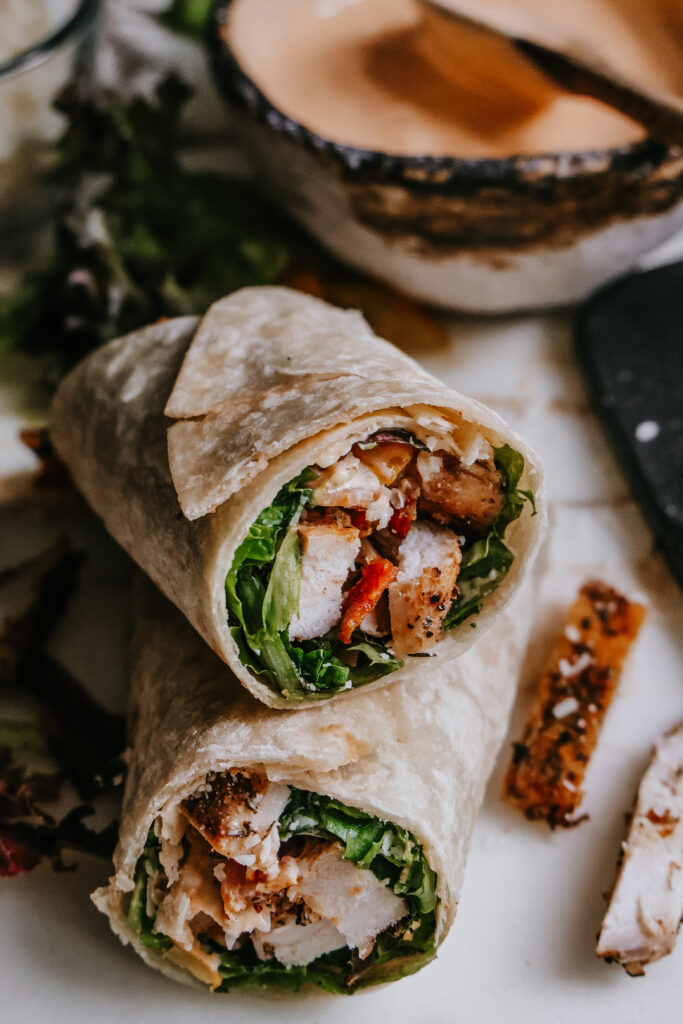Two BLT chicken wrap halves stacked showing the lettuce, chicken, and bacon filling