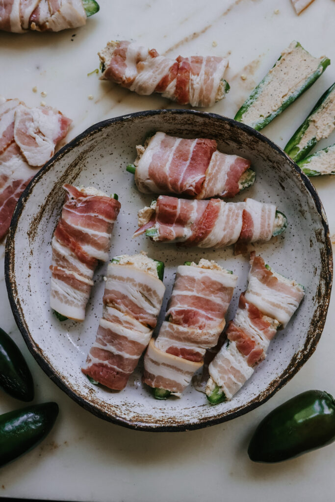 Bacon wrapped jalapeno poppers on a plate before air frying