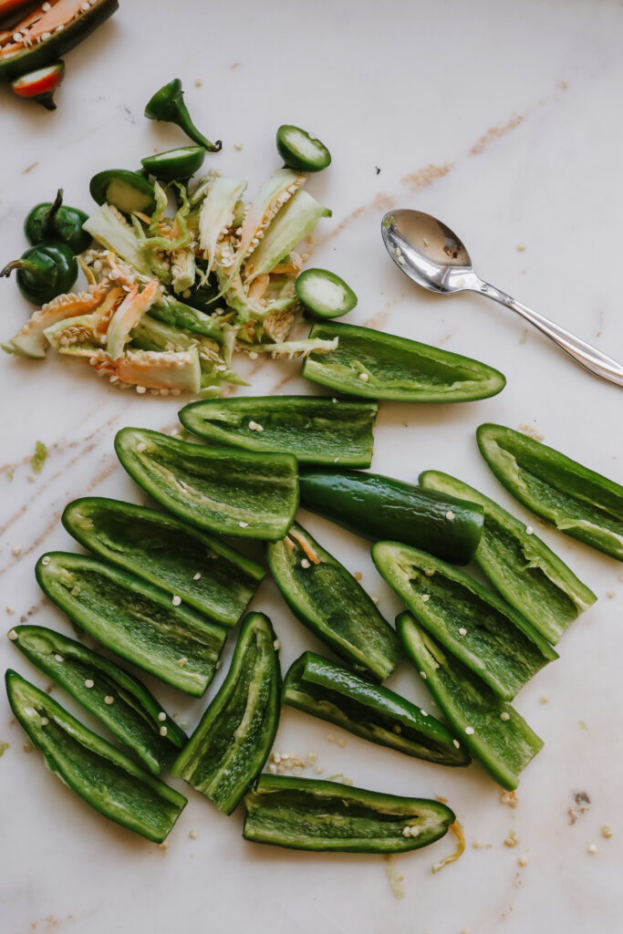 Jalapeno halves with seeds and membranes scraped out on a marble counter