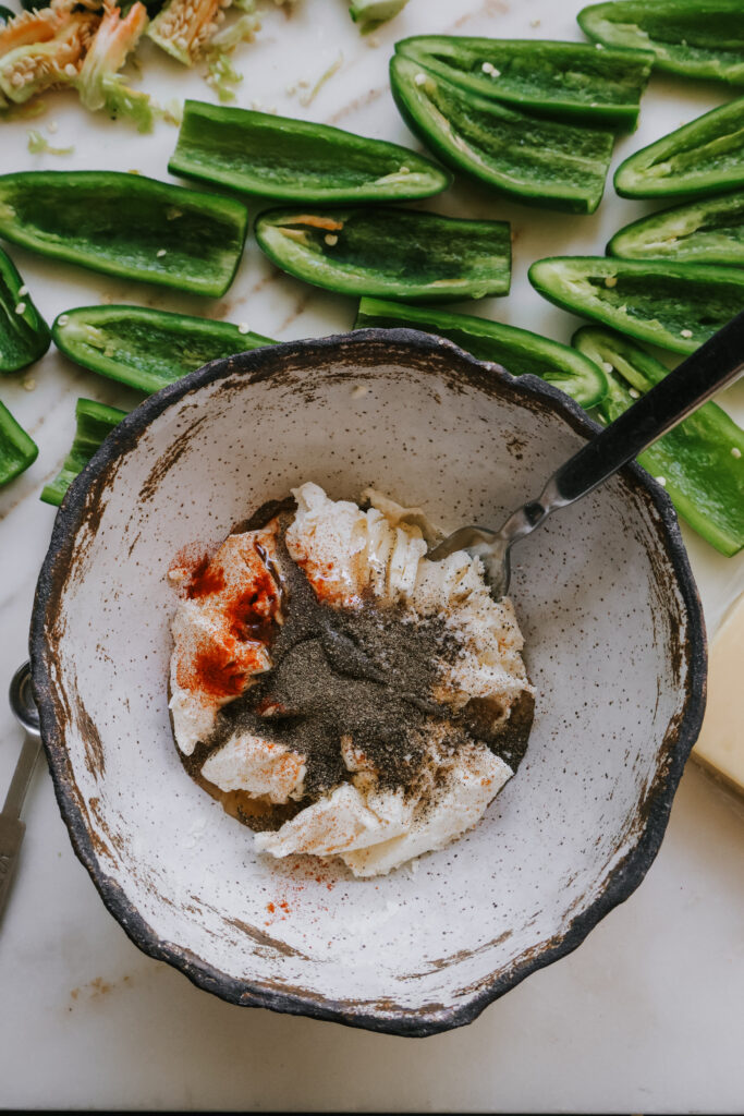 Cream cheese, smoked paprika, and seasonings in a bowl before mixing for jalapeno popper filling