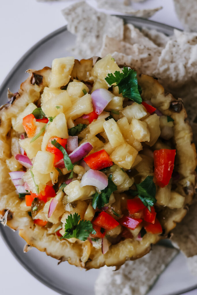 Fresh pineapple salsa recipe in a pineapple bowl surrounded by tortilla chips