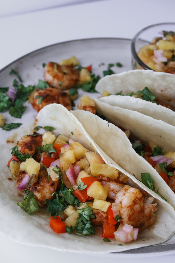 Plated shrimp tacos with pineapple salsa showing seared shrimp, diced pineapple, and red onion.