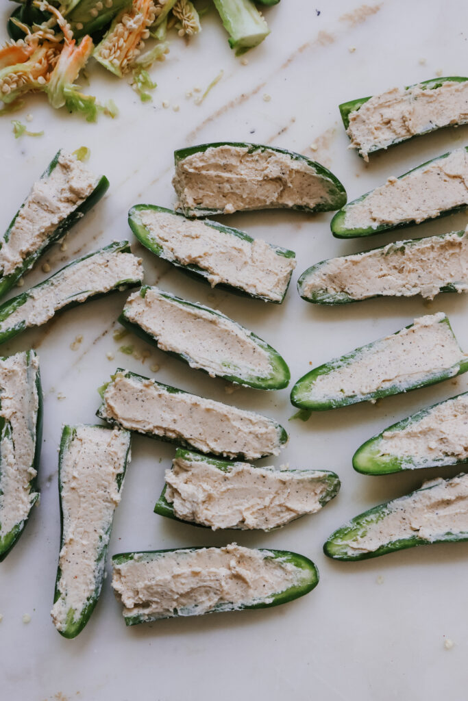 Jalapeno halves stuffed with cream cheese filling, ready to wrap in bacon