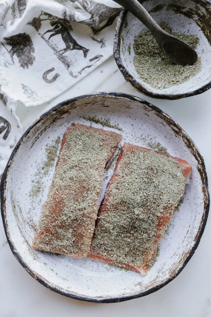Salmon fillets coated in brown sugar spice rub on a speckled plate