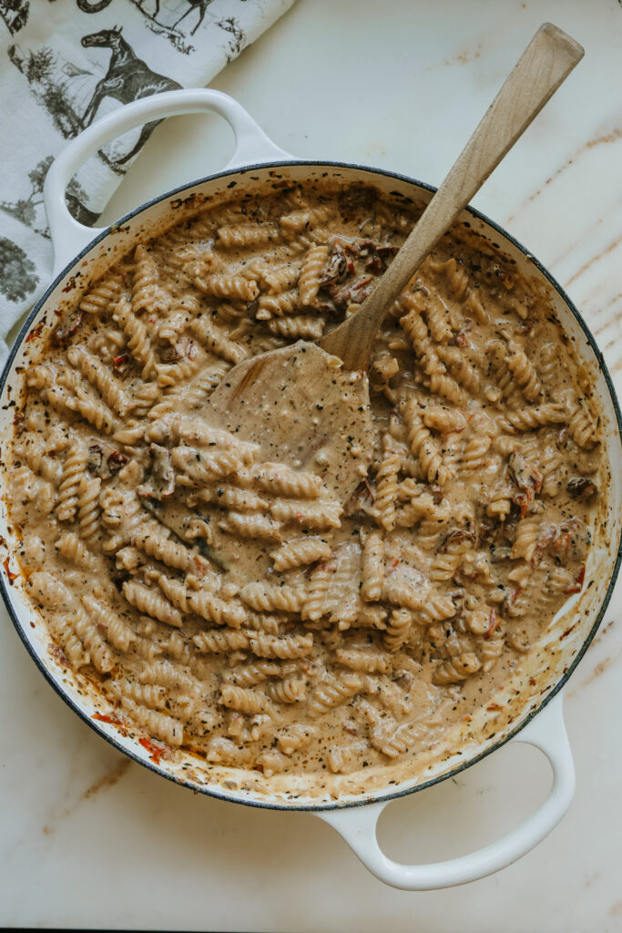 Creamy sun-dried tomato pasta stirred together in a skillet
