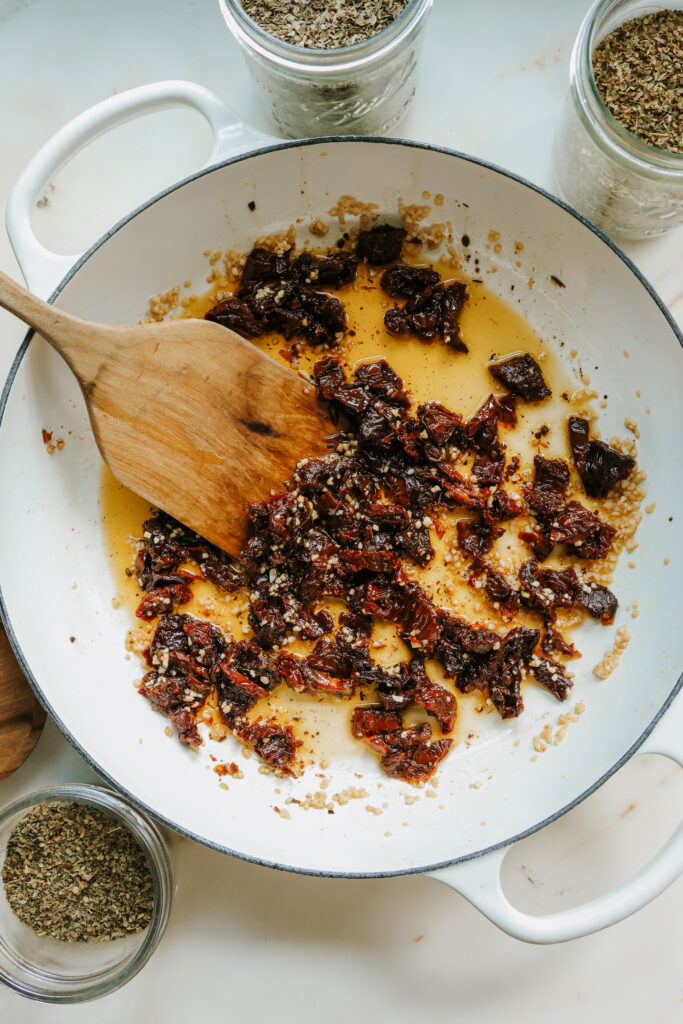 Sun-dried tomatoes and garlic sautéing in a skillet for creamy sun-dried tomato pasta